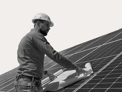 Ein Techniker mit Bauhelm inspiziert eine Photovoltaik-Anlage, Symbol für die nachhaltige Stromproduktion von medl.